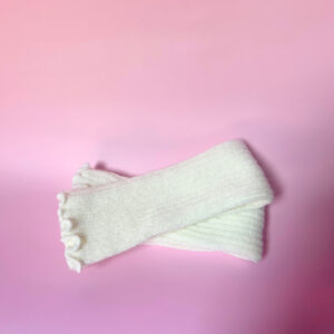 Cream ribbed knit leg warmers displayed on a pink background