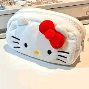 White Hello Kitty plush pencil case with red bow and zipper, used as a stationery or makeup bag